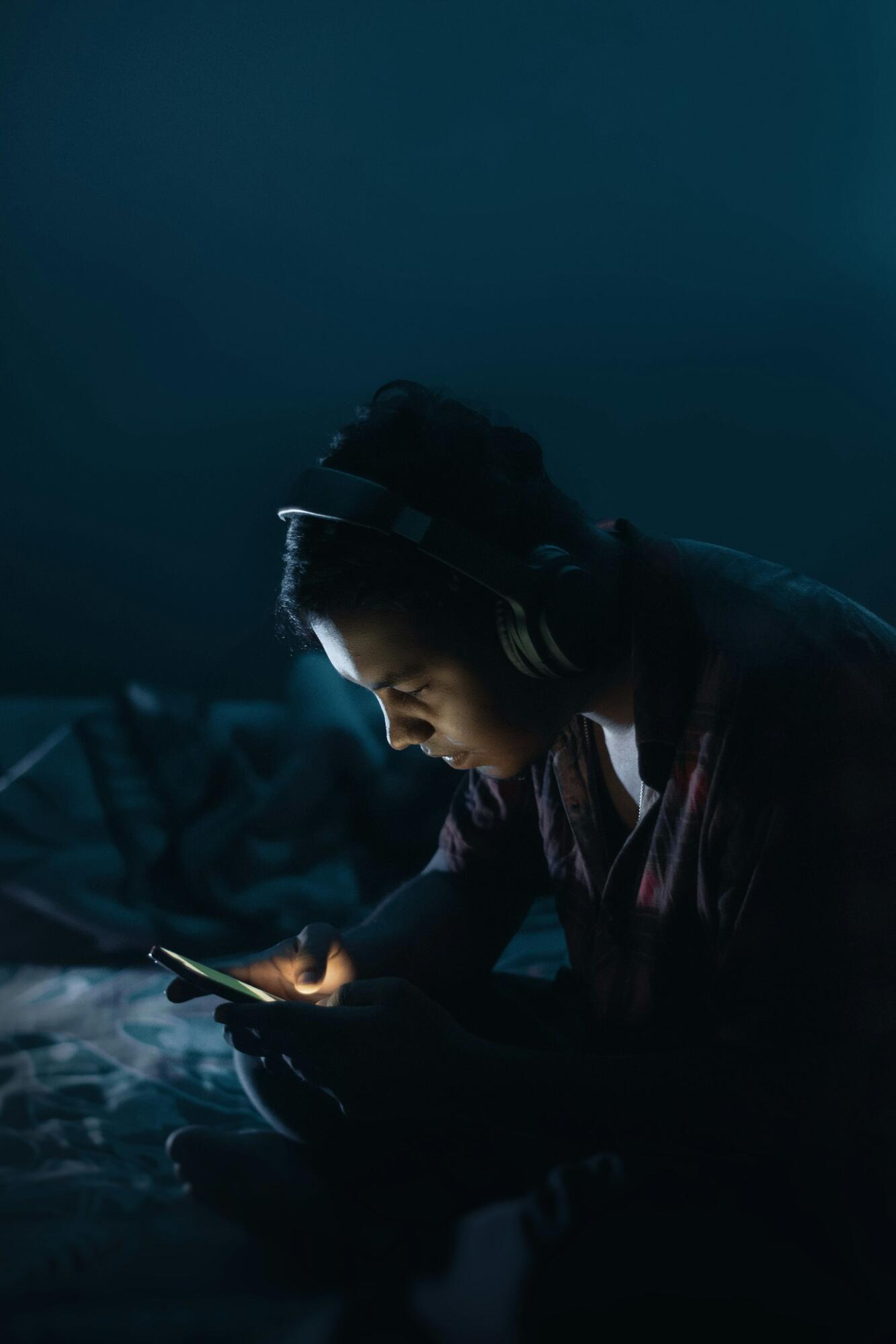 A player in headphones, lit by a screen in a dark room